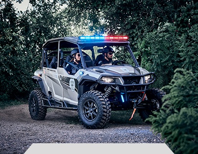 2 law enforcement officers riding in a Polaris GENERAL XP 4 1000 side-by-side that has law enforcement package accessories installed.