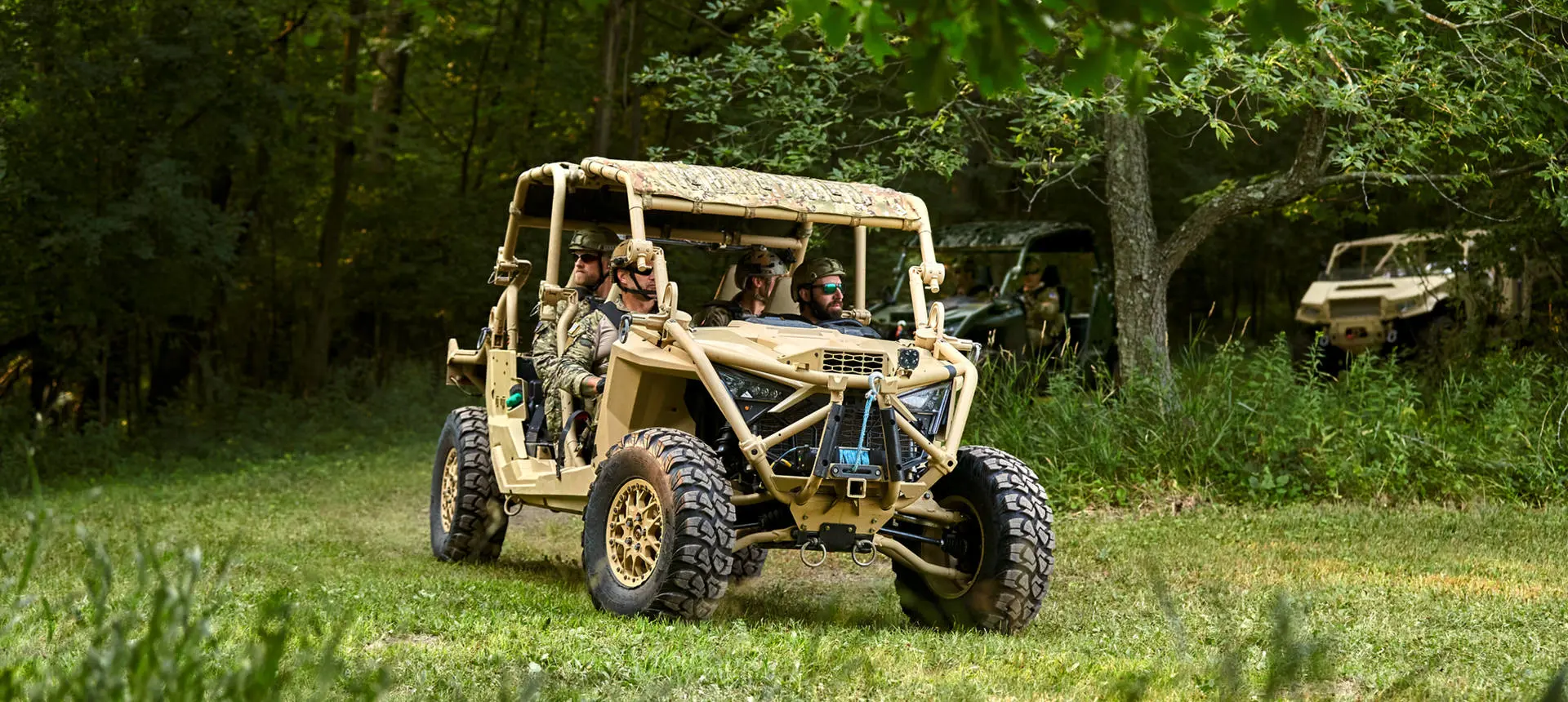 An MRZR Alpha military tactical side-by-side leading a group of tactical off-road vehicles.