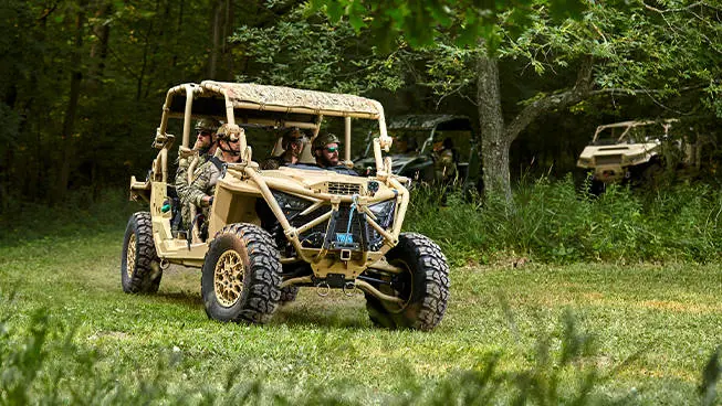 An MRZR Alpha military tactical side-by-side leading a group of tactical off-road vehicles.