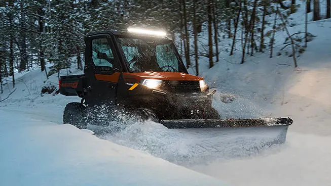 A Polaris RANGER 1000 UTV plowing snow in the winter.