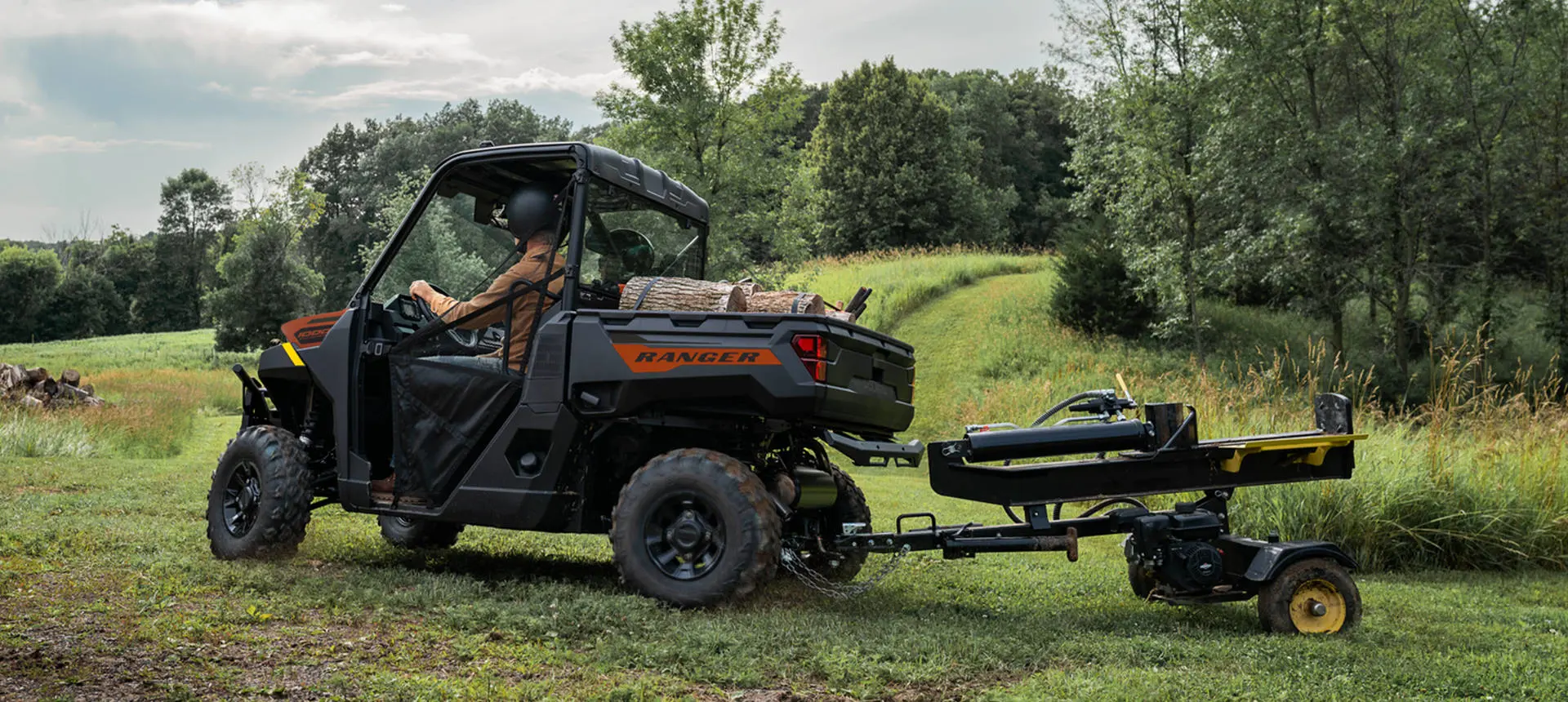 A Polaris RANGER 1000 UTV pulling a log splitter attached to the rear hitch.