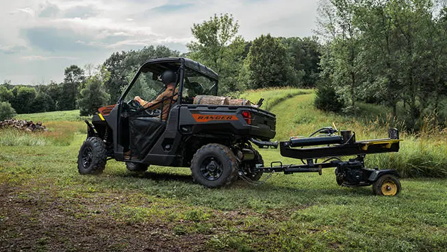 A Polaris RANGER 1000 UTV pulling a log splitter attached to the rear hitch.
