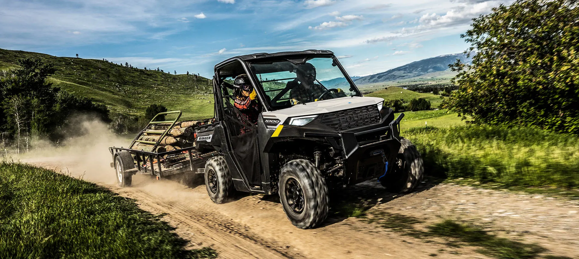 A Polaris RANGER 1000 UTV pulling a heavy trailer loaded with gates and fence posts.