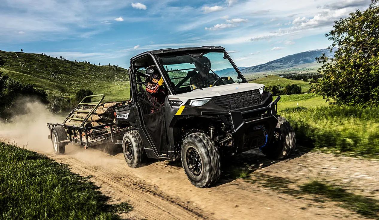 A Polaris RANGER 1000 UTV pulling a heavy trailer loaded with gates and fence posts.