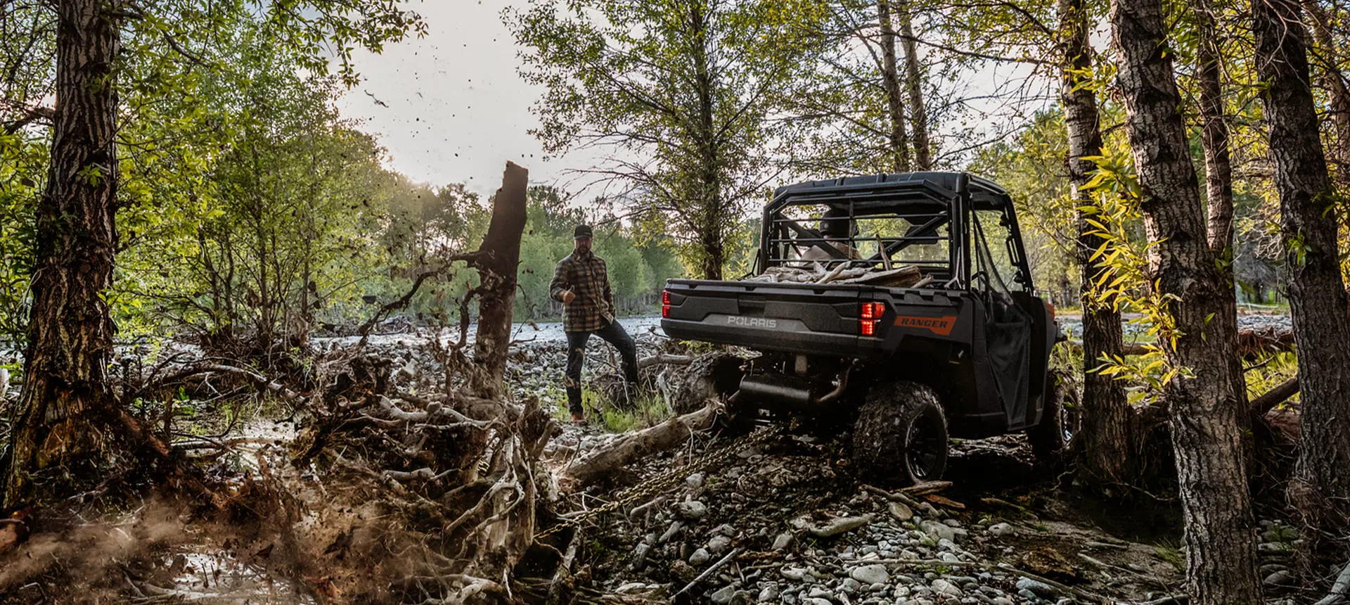 A Polaris RANGER 1000 UTV pulling out tree roots with a chain attached to the rear hitch.