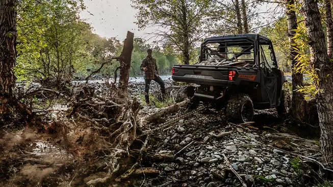 A Polaris RANGER 1000 UTV pulling out tree roots with a chain attached to the rear hitch.