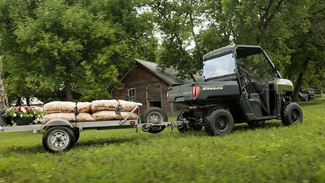 A Sage Green Polaris RANGER 500 UTV pulling a trailer loaded with mulch.