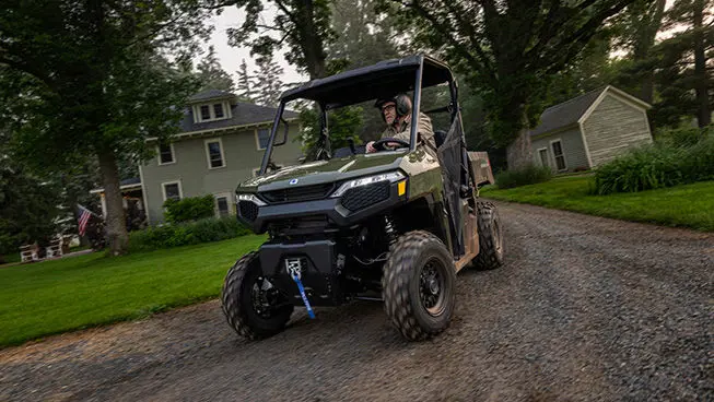 A man driving a Sage Green Polaris RANGER 500 UTV on his driveway.