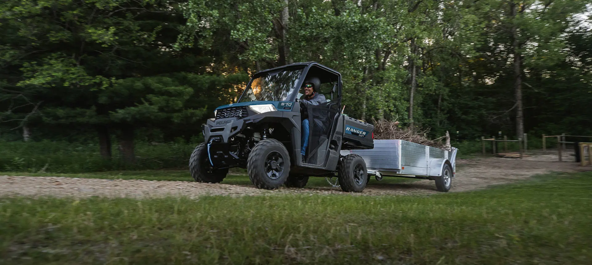 A Polaris RANGER SP 570 UTV pulling a trailer loaded with branches and other tree trimmings.