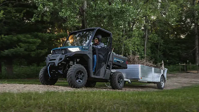 A Polaris RANGER SP 570 UTV pulling a trailer loaded with branches and other tree trimmings.