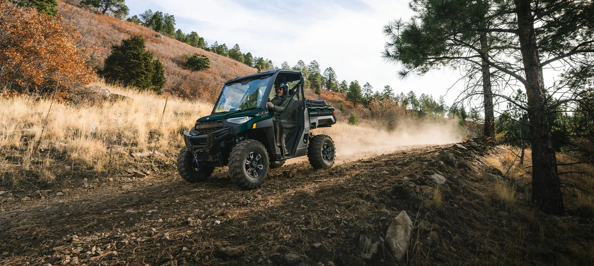 2 riders in a Polaris RANGER XP 1000 UTV cruising downhill on a trail.