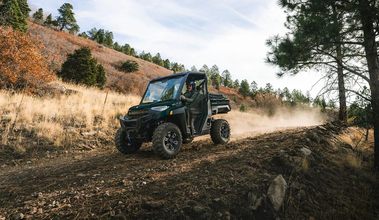 2 riders in a Polaris RANGER XP 1000 UTV cruising downhill on a trail.