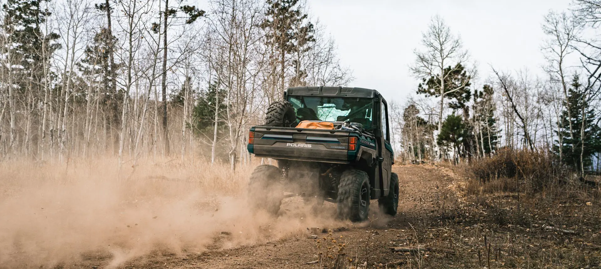 Rear-view of a Polaris RANGER XP 1000 NorthStar Edition UTV on a dusty trail.