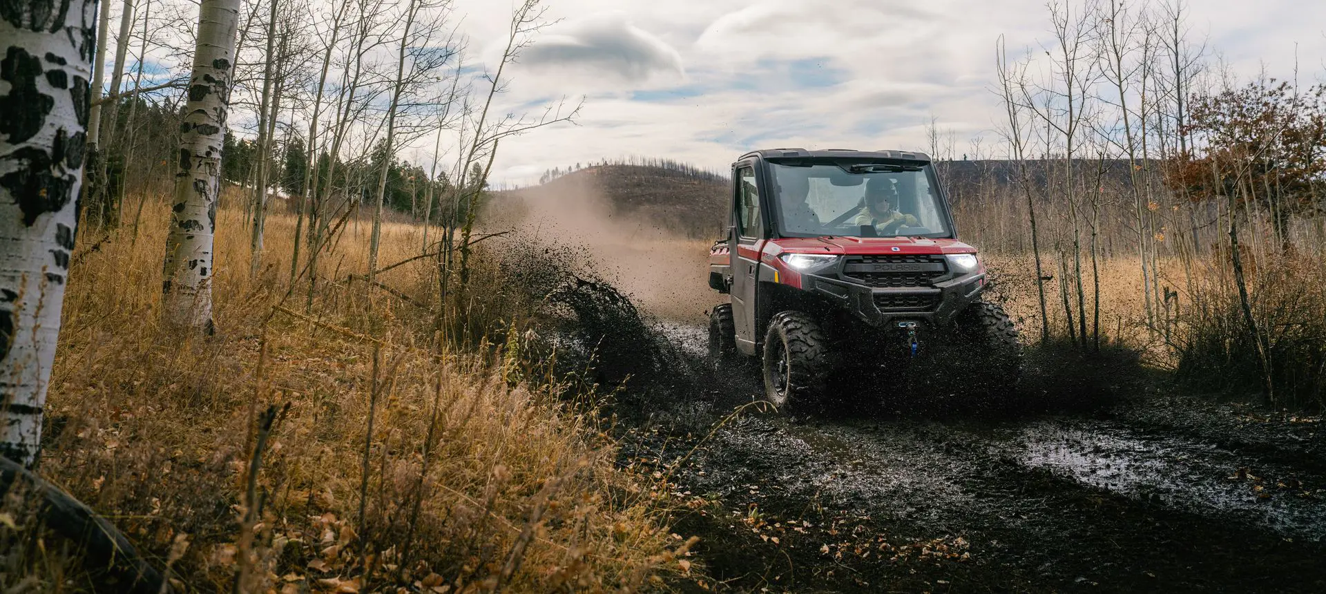A Polaris RANGER XP 1000 NorthStar Edition UTV driving through mud.