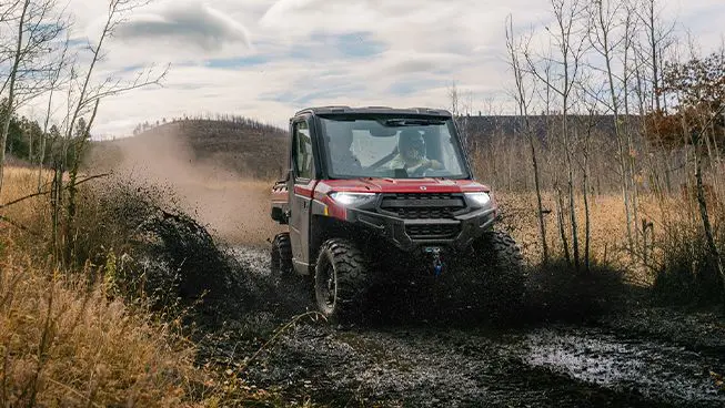 A Polaris RANGER XP 1000 NorthStar Edition UTV driving through mud.