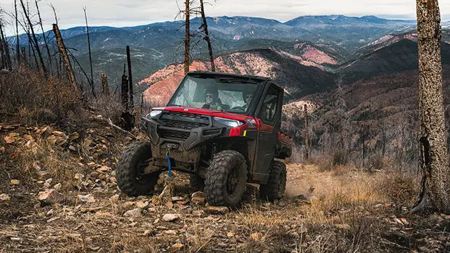 A Polaris RANGER XP 1000 NorthStar Edition UTV climbing uphill over rocky terrain.