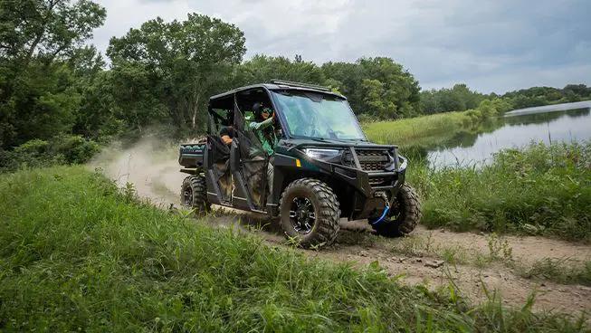 4 riders in a  Polaris RANGER CREW XP 1000 UTV driving on a trail near a lake.