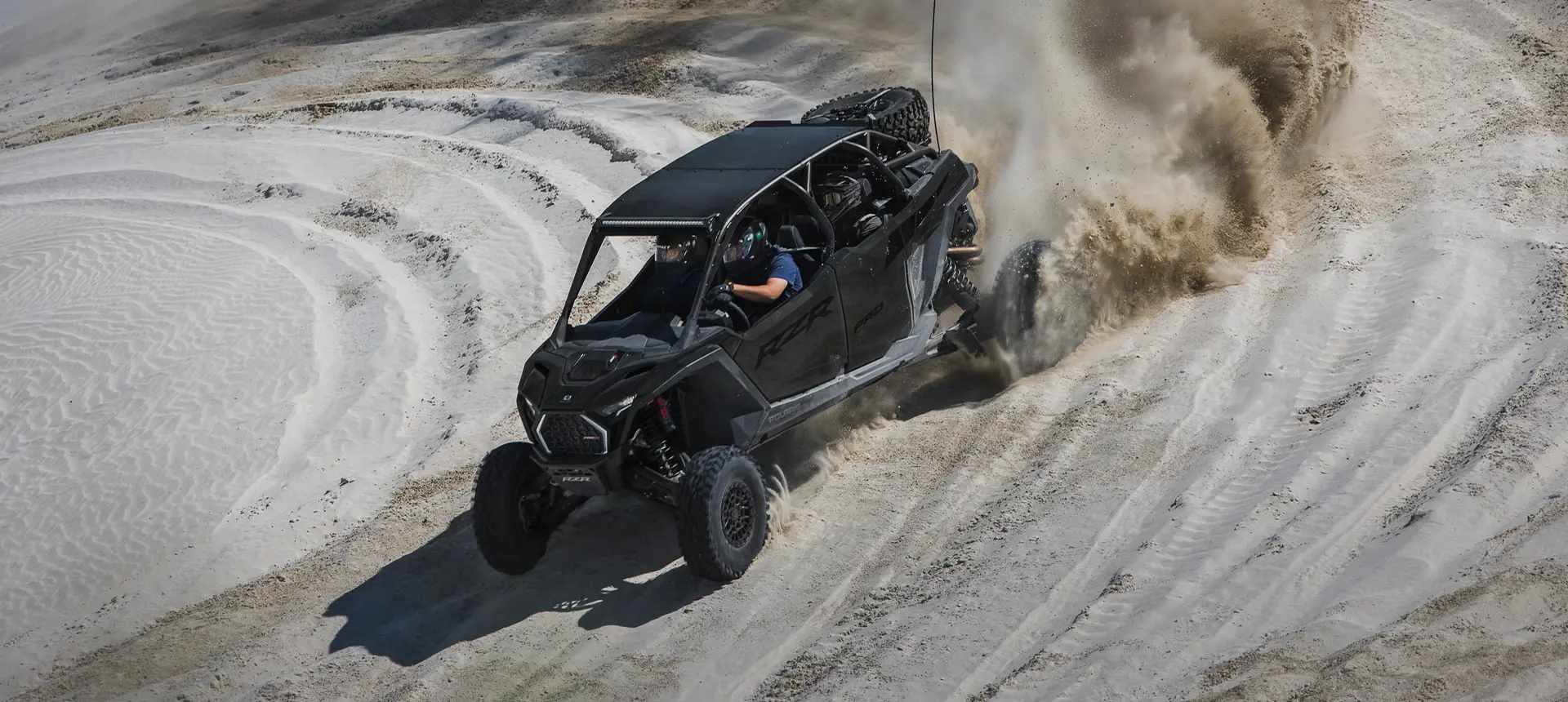 A Super Graphite Polaris RZR Pro R 4 side-by-side taking a tight corner in the desert.