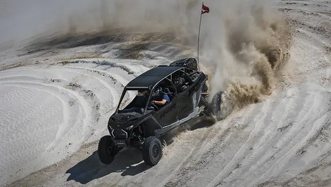 A Super Graphite Polaris RZR Pro R 4 side-by-side taking a tight corner in the desert.