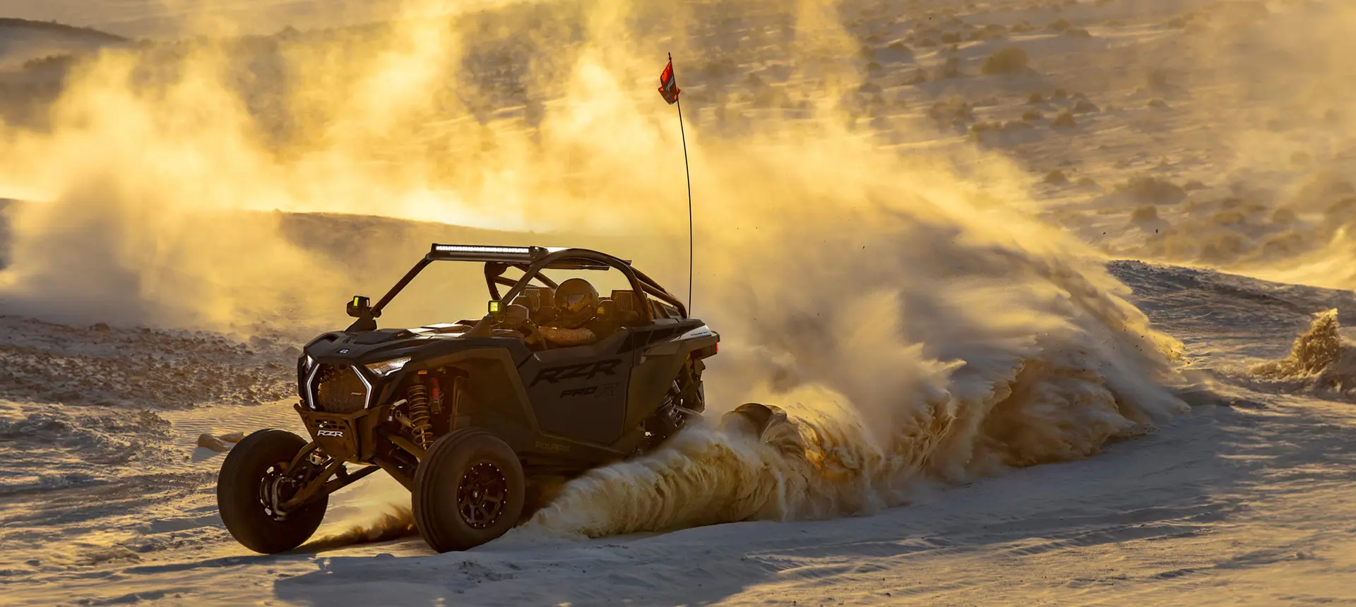 A Polaris RZR Pro R side-by-side throwing sand in the dunes.