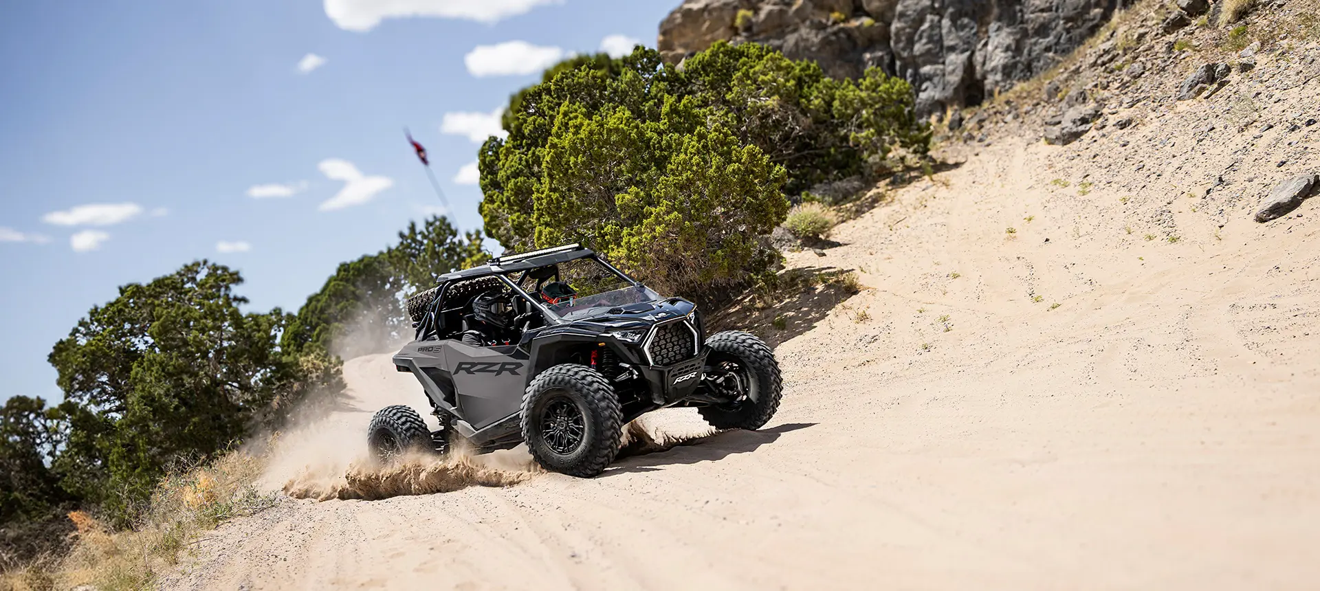2 riders in a Polaris RZR Pro S side-by-side cornering in the desert.