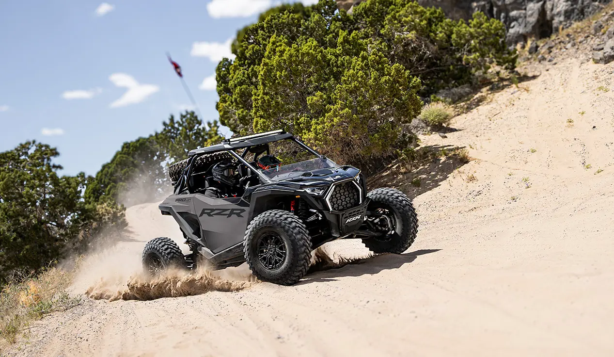 2 riders in a Polaris RZR Pro S side-by-side cornering in the desert.