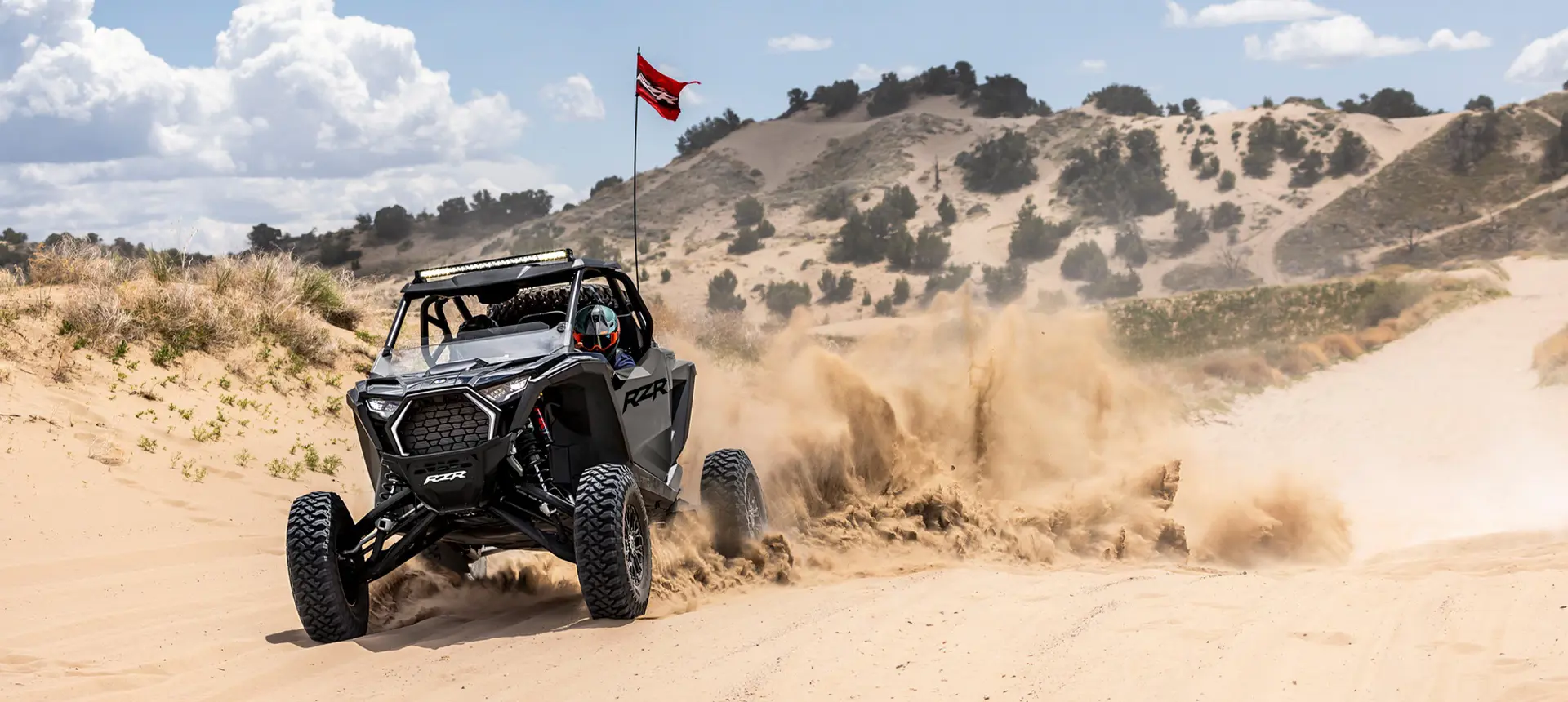 Polaris RZR Pro S side-by-side with headlights illuminated and driving through the desert.