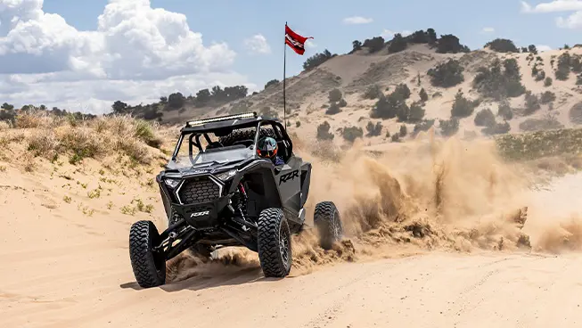 Polaris RZR Pro S side-by-side with headlights illuminated and driving through the desert.
