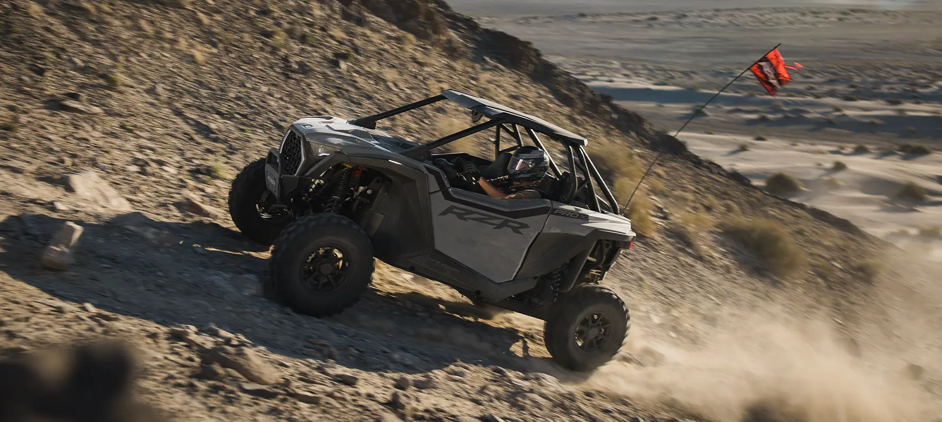 A Polaris RZR Pro XP side-by-side climbing a rocky hill.