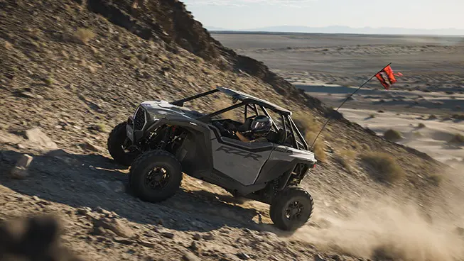 A Polaris RZR Pro XP side-by-side climbing a rocky hill.