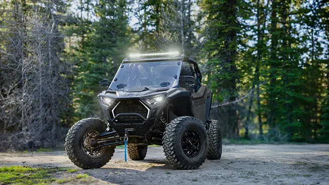 Front end view of a Polaris RZR Pro XP side-by-side with a lightbar and headlights illuminated.