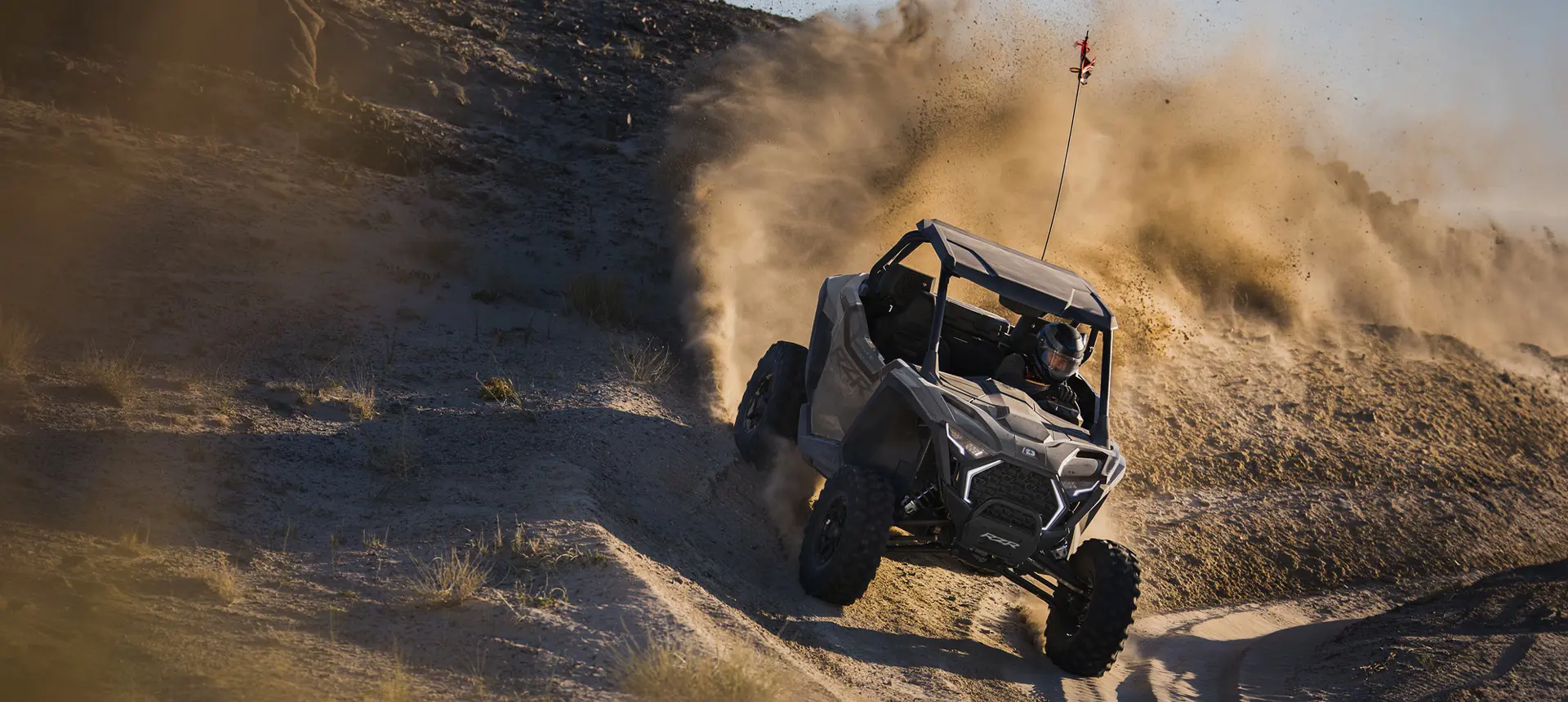 A Polaris RZR Pro XP side-by-side taking a tight corner and throwing sand.