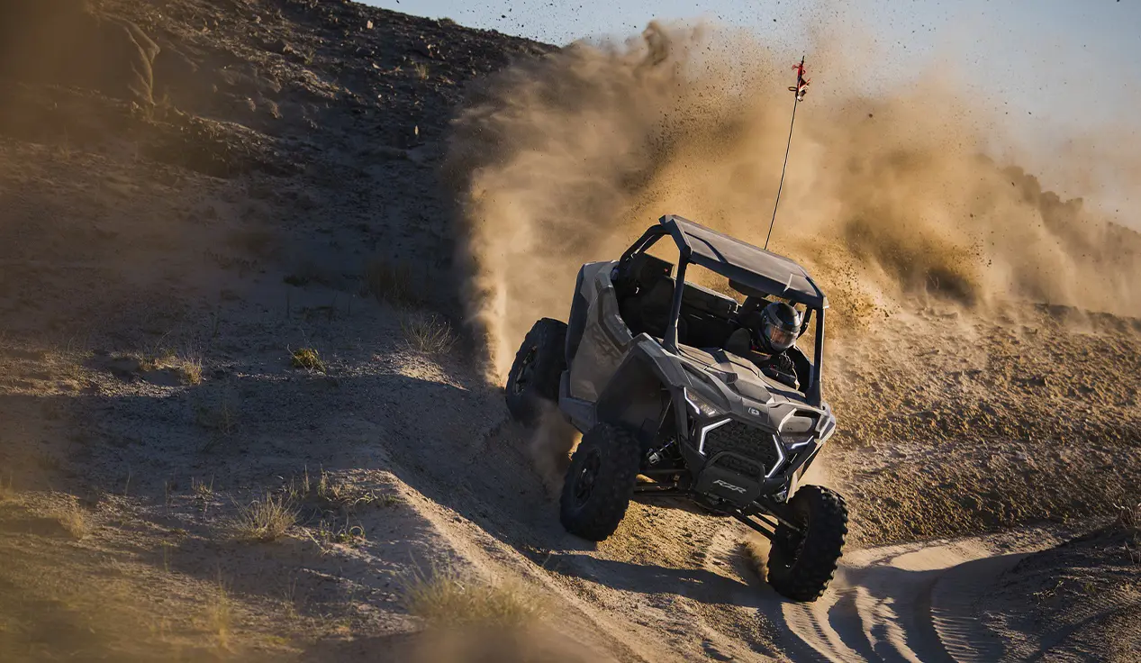 A Polaris RZR Pro XP side-by-side taking a tight corner and throwing sand.