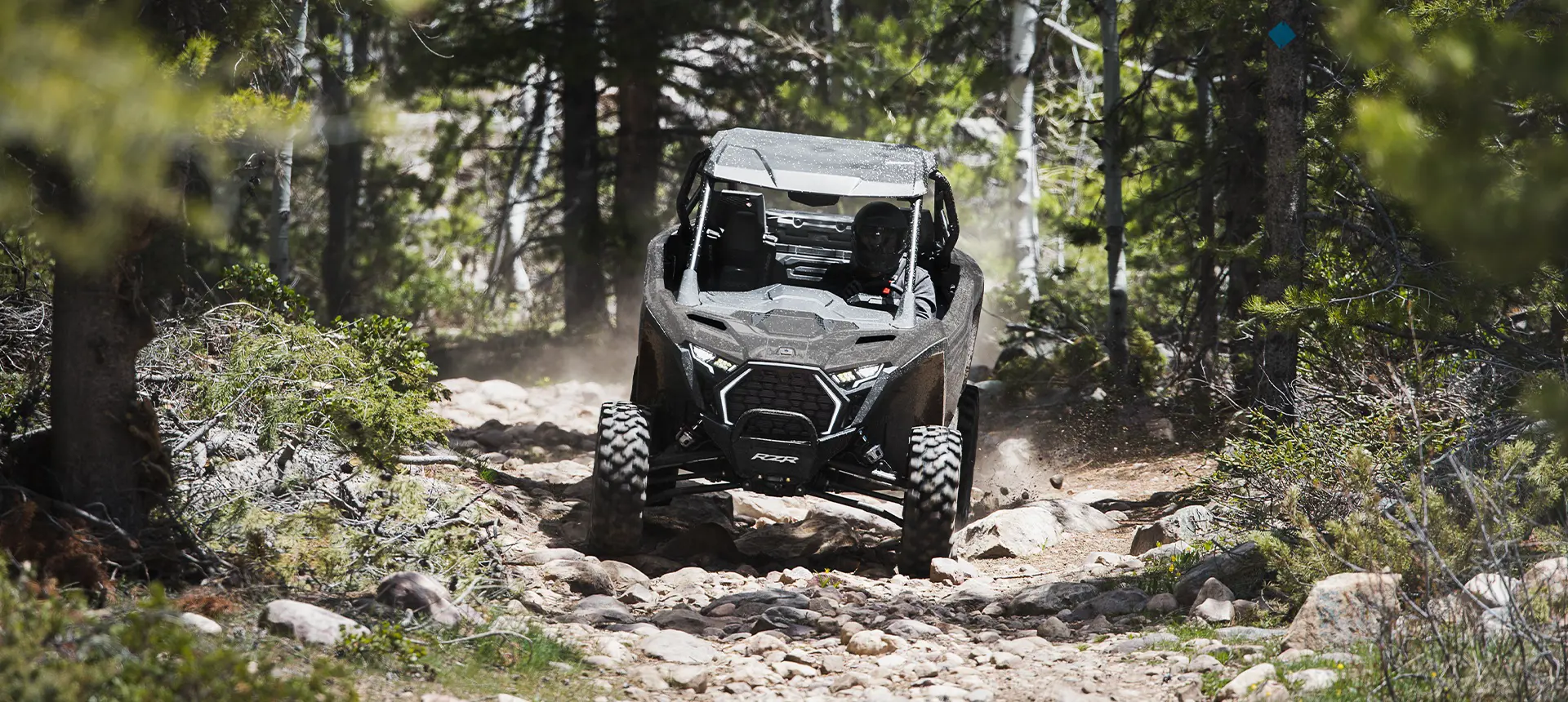 A Polaris RZR Pro XP side-by-side driving out of the forest while trail riding.