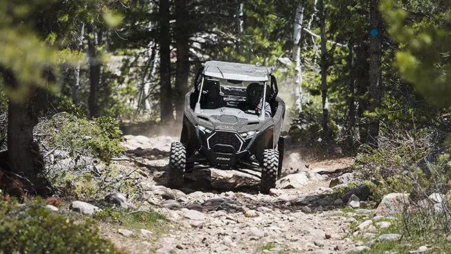 A Polaris RZR Pro XP side-by-side driving out of the forest while trail riding.