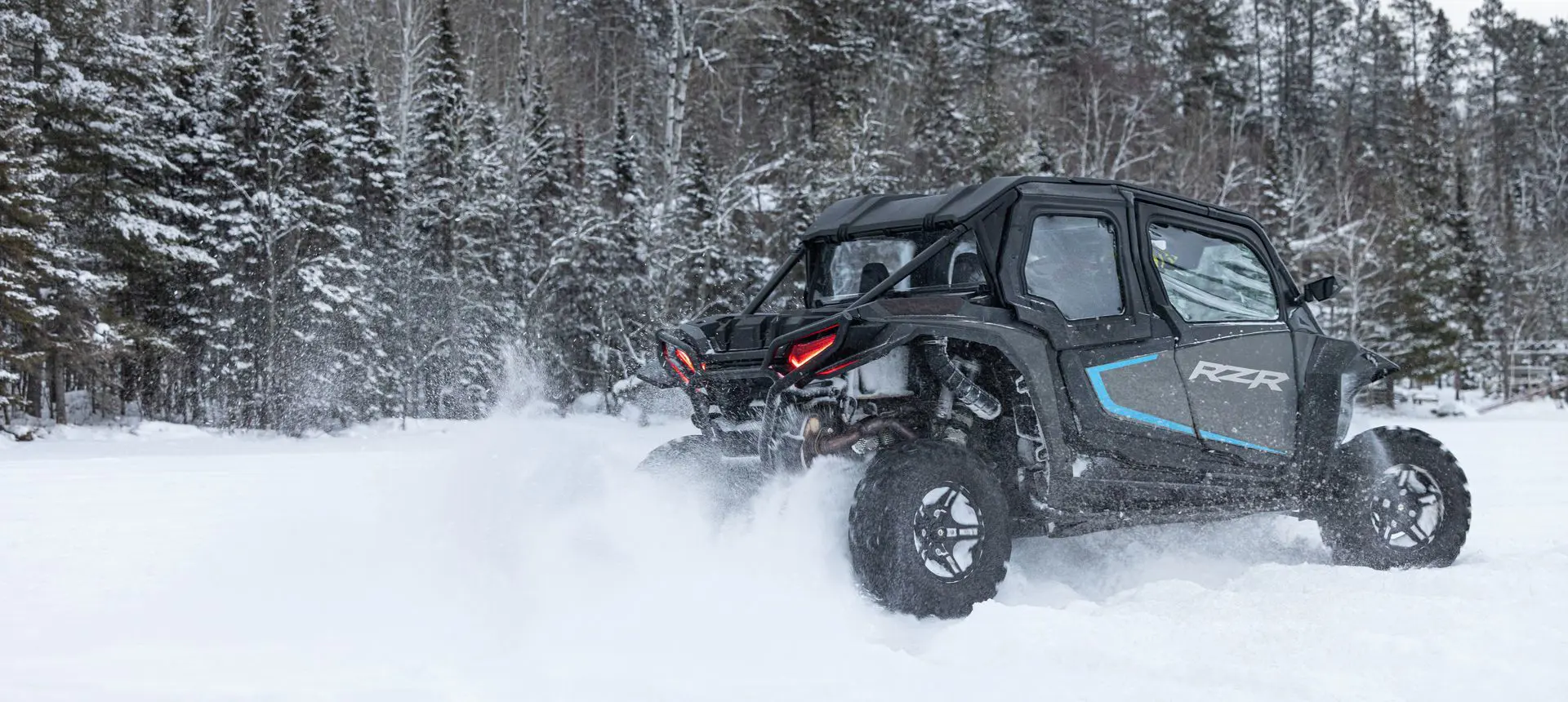Side profile of a RZR XP side-by-side driving in the winter.