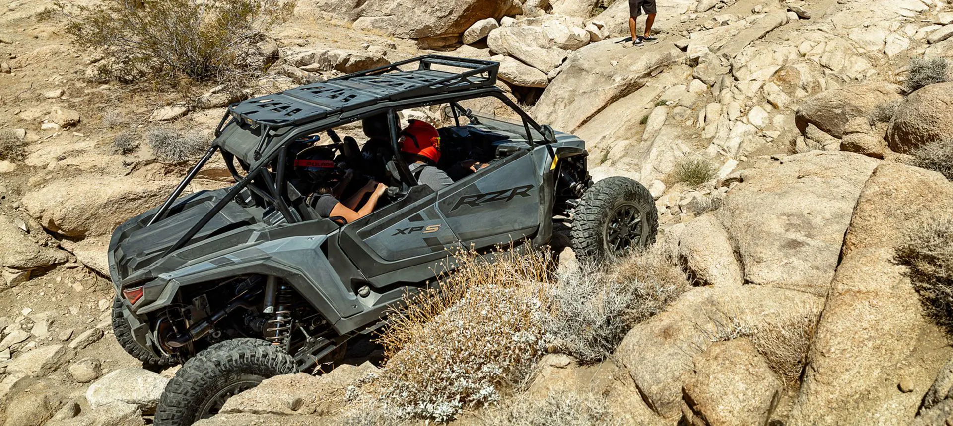 A RZR XP S 4 side-by-side climbing up a rocky hill.