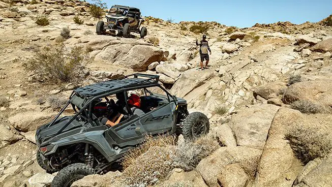 A RZR XP S 4 side-by-side climbing up a rocky hill.
