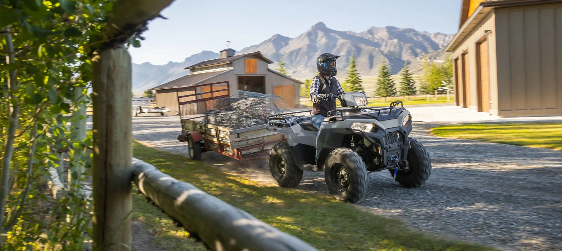 Polaris Sportsman 450 ATV pulling a trailer loaded with heavy fence.