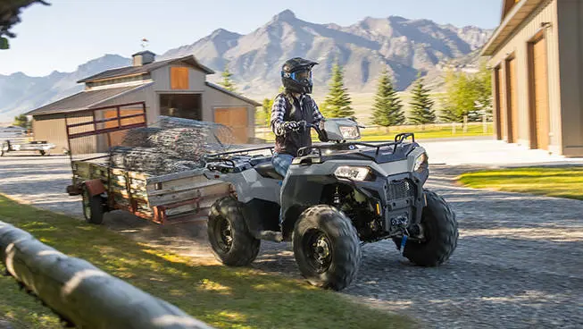 Polaris Sportsman 450 ATV pulling a trailer loaded with heavy fence.