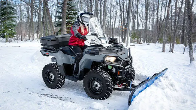 Polaris Sportsman 450 ATV with a plow attached in the winter.