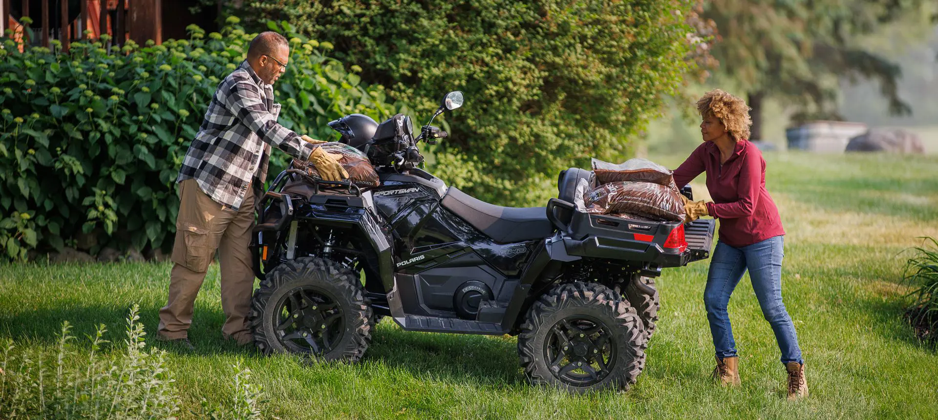 2 people loading mulch onto the cargo racks of a Polaris Sportsman 570 ATV.