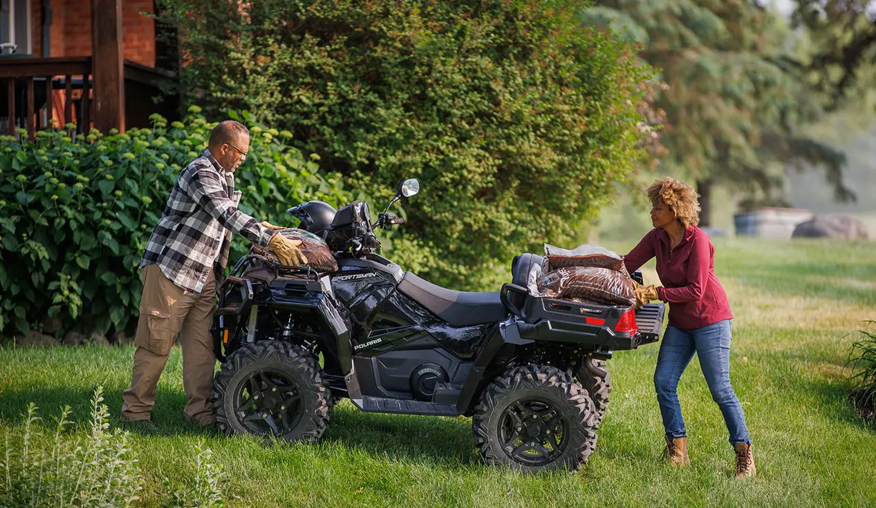 2 people loading mulch onto the cargo racks of a Polaris Sportsman 570 ATV.