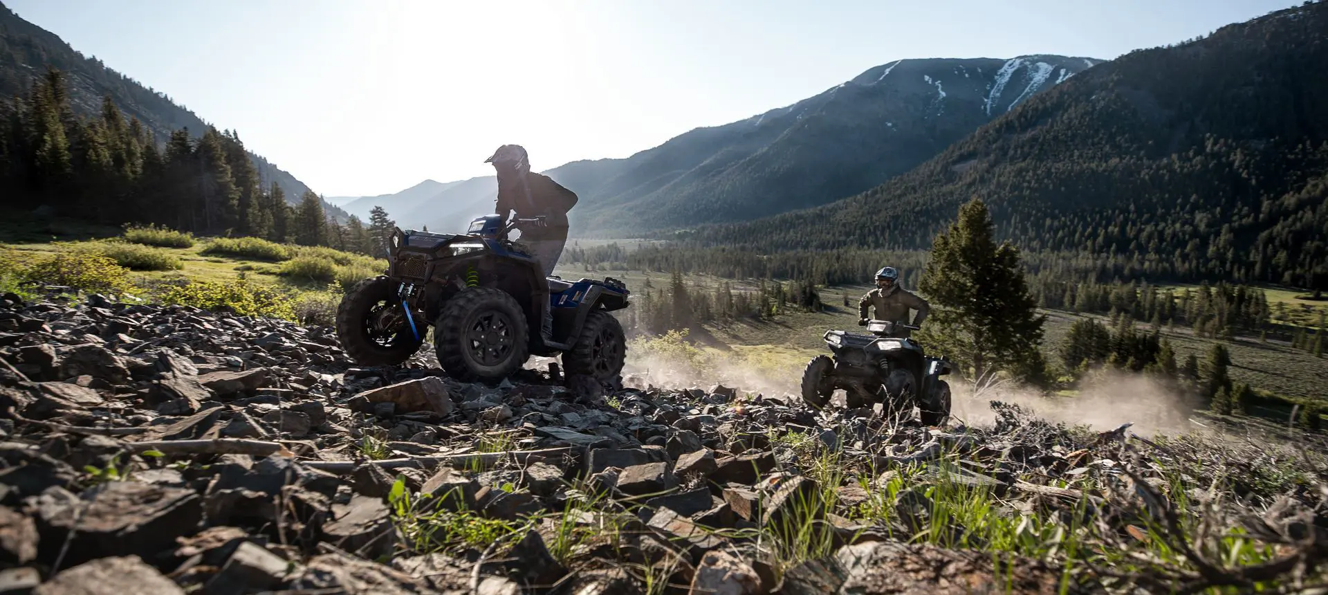 Two Polaris Sportsman 850 ATVs climbing over rocky terrain with ease.