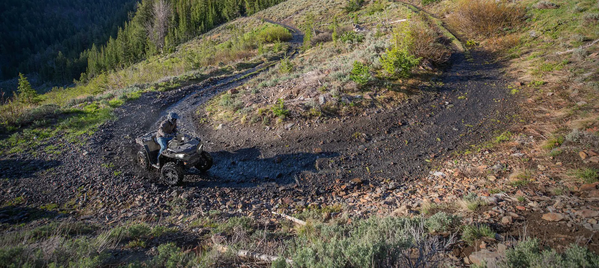 A rider on a Polaris Sportsman 850 ATV taking a tight corner in the mud.