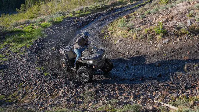 A rider on a Polaris Sportsman 850 ATV taking a tight corner in the mud.