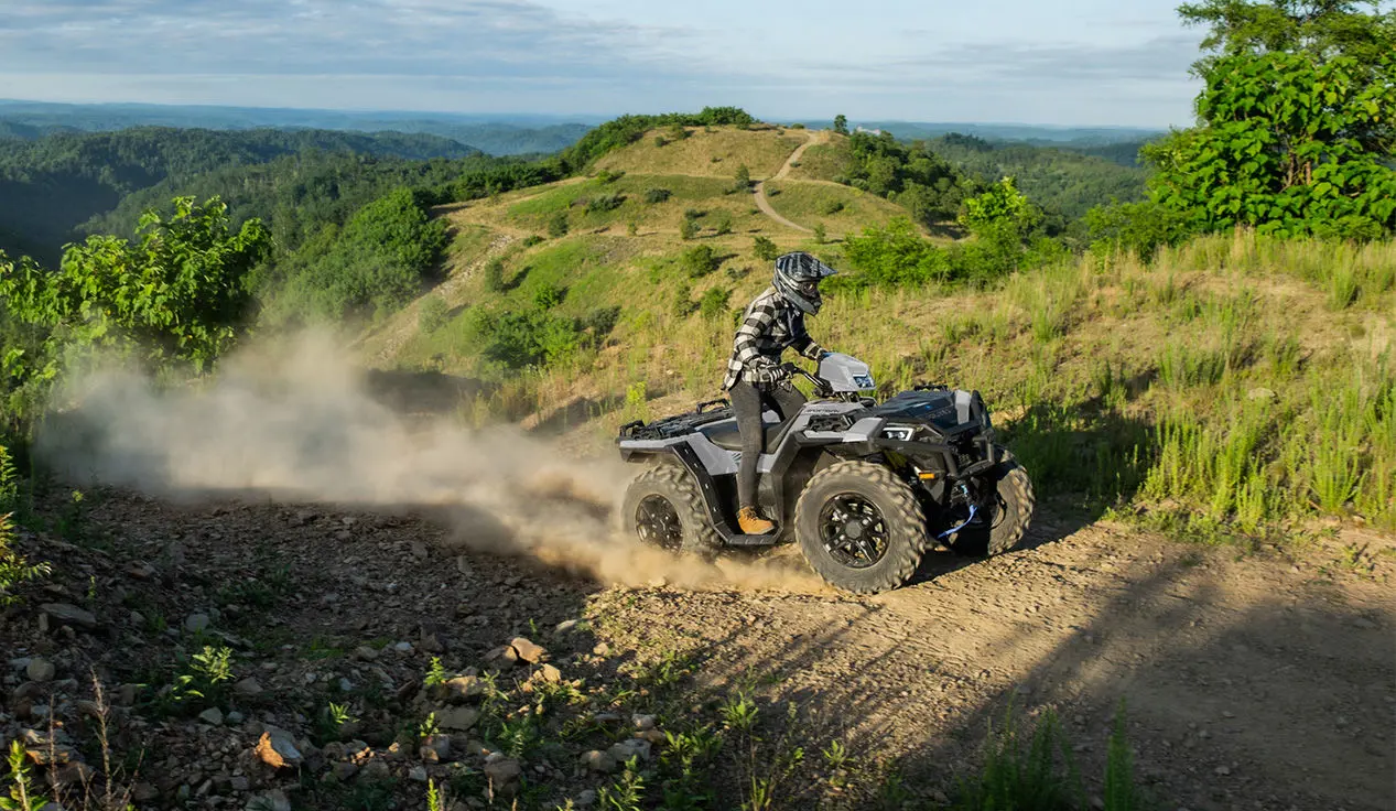 A rider on a  Polaris Sportsman XP 1000 ATV driving on a hilly trail.