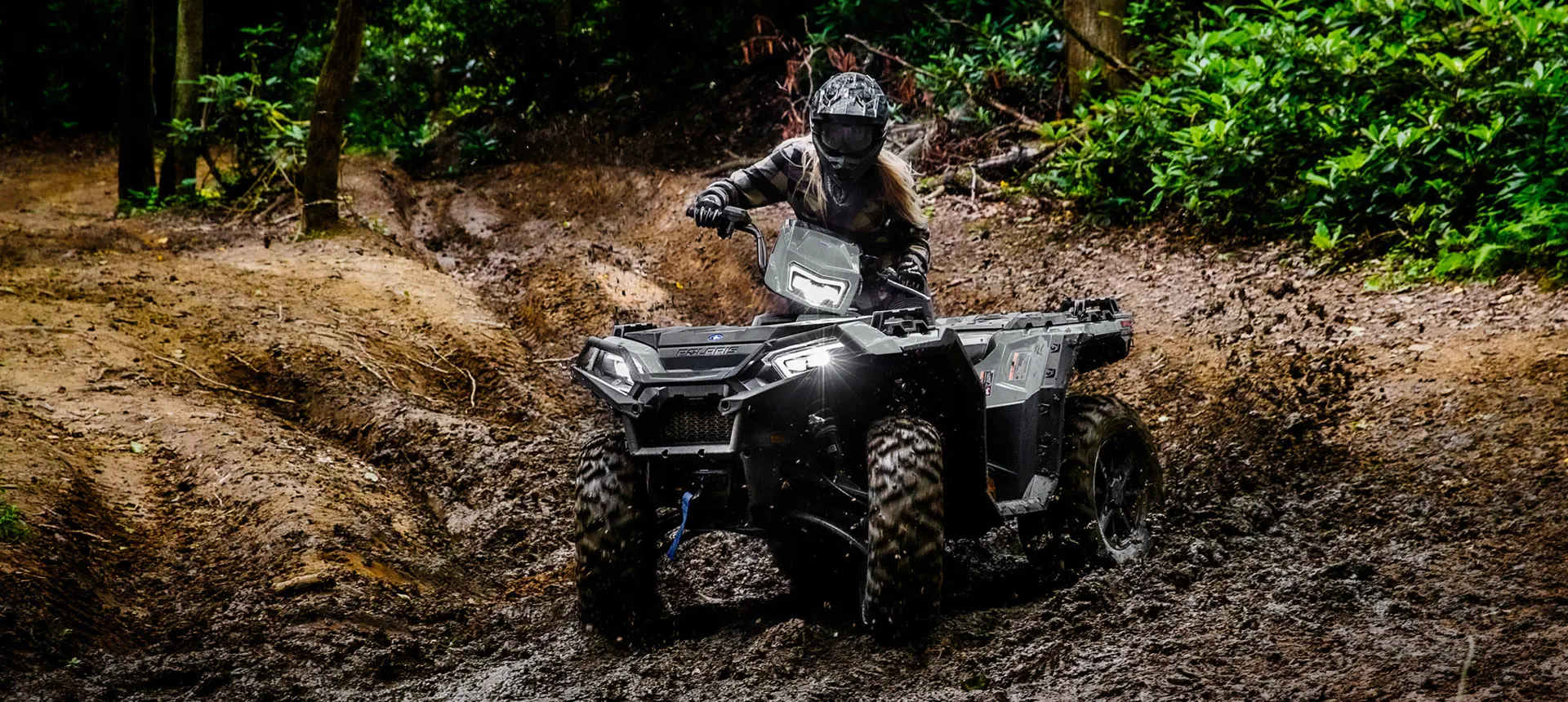 Person cruising through mud on a Polaris Sportsman XP 1000 ATV.