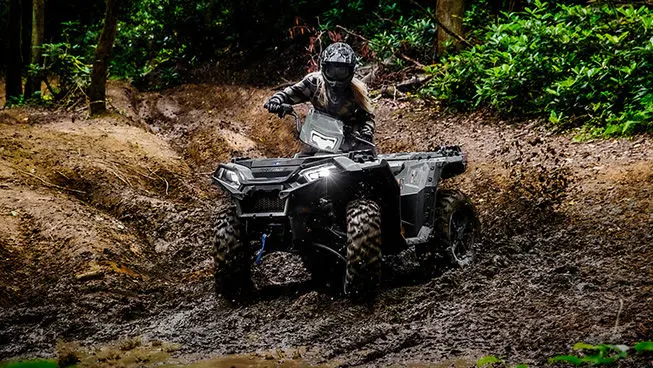 Person cruising through mud on a Polaris Sportsman XP 1000 ATV.