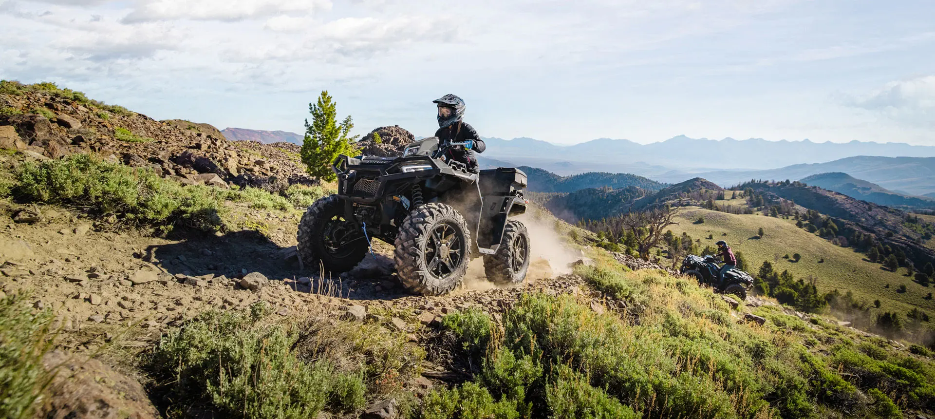 A rider on a Polaris Sportsman XP 1000 Ultimate ATV driving on a hillside.